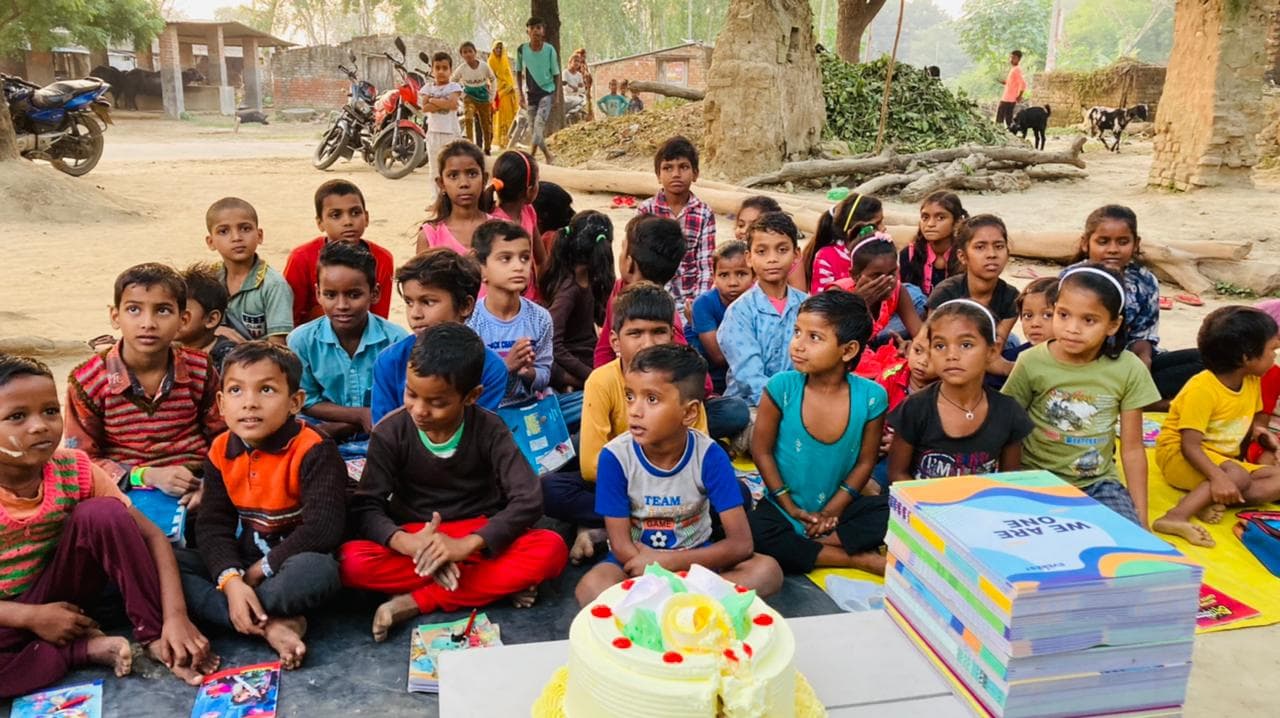 A large group of village children gathered together with donated books during an Ayushman Foundation outreach day