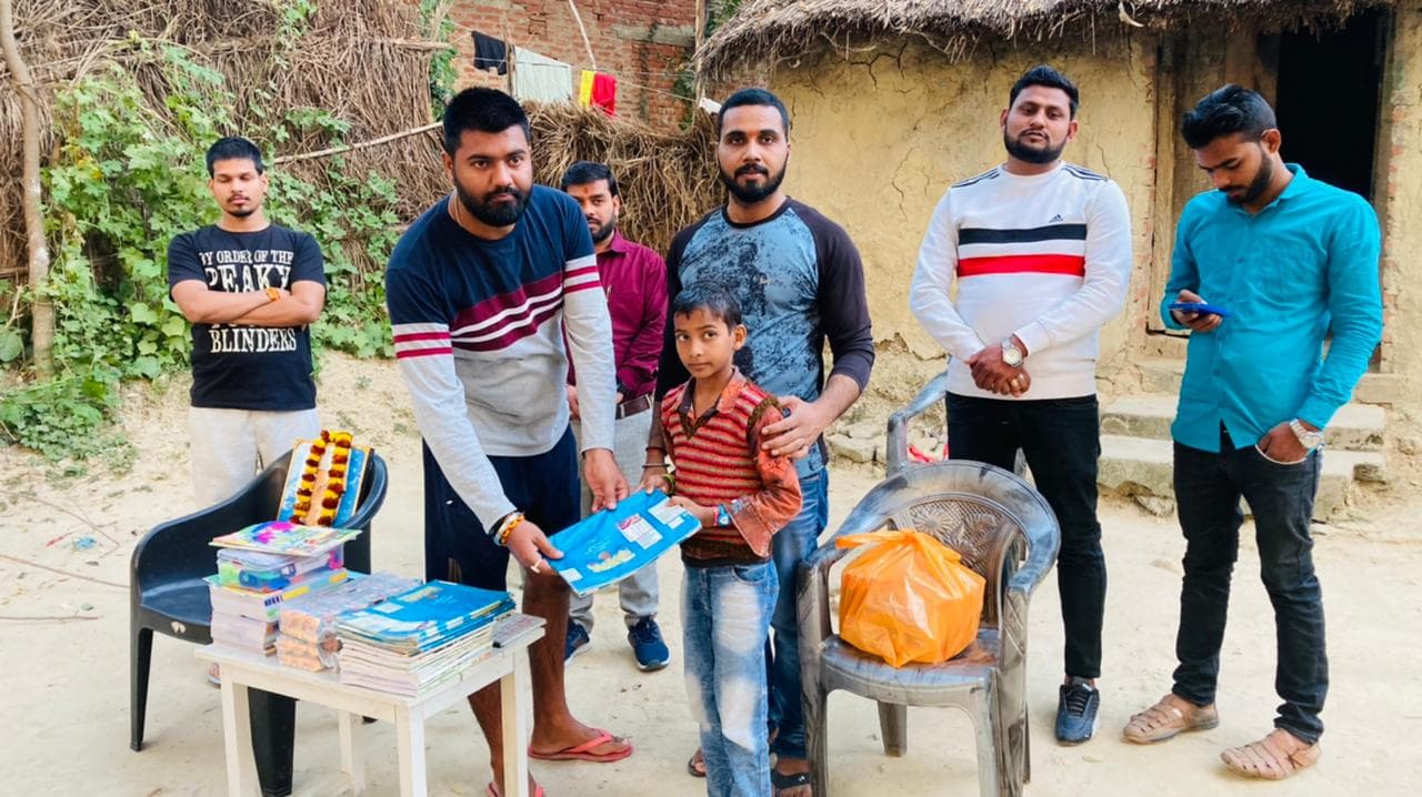 A young boy receiving a book donation at his home from Ayushman Foundation volunteers